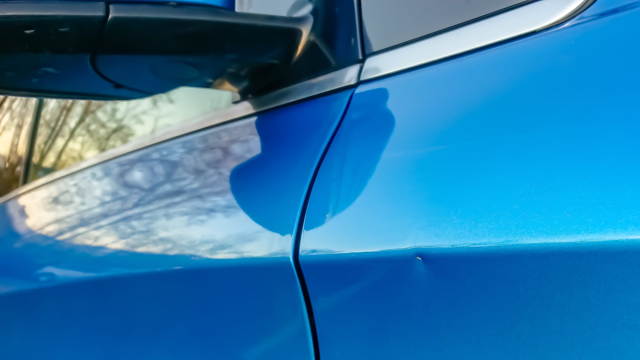 A small dent in the fender of a blue metallic European car Image of a small dent in the fender of a blue metallic European car